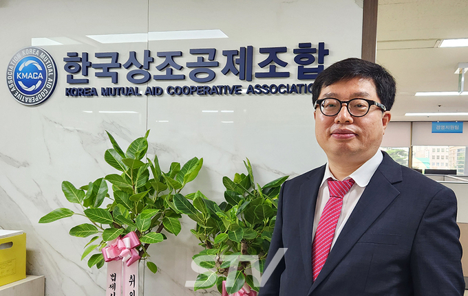 조기열 한국상조공제조합 7대 이사장이 서울 마포구 공덕동 조합 사무실에서 로고 앞에서 포즈를 취하고 있다. 조 이사장은 "상조는 인간의 아름다운 마무리를 도와준다"라고 했다.